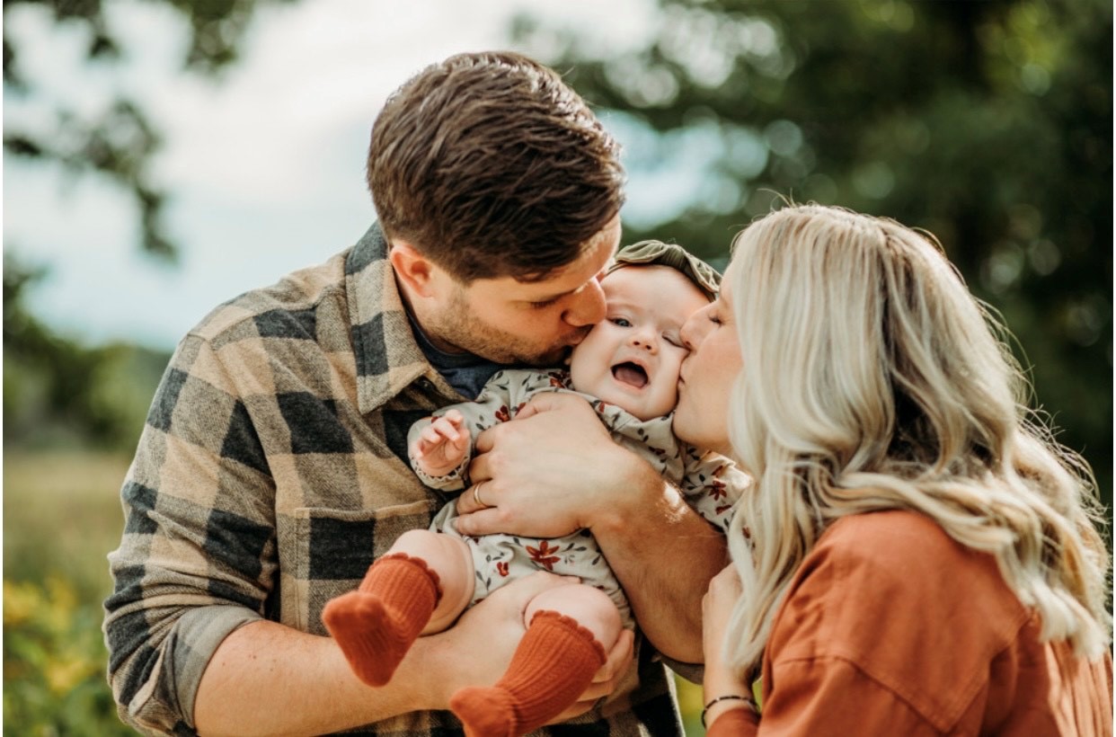 Mom and dad kissing baby's cheeks