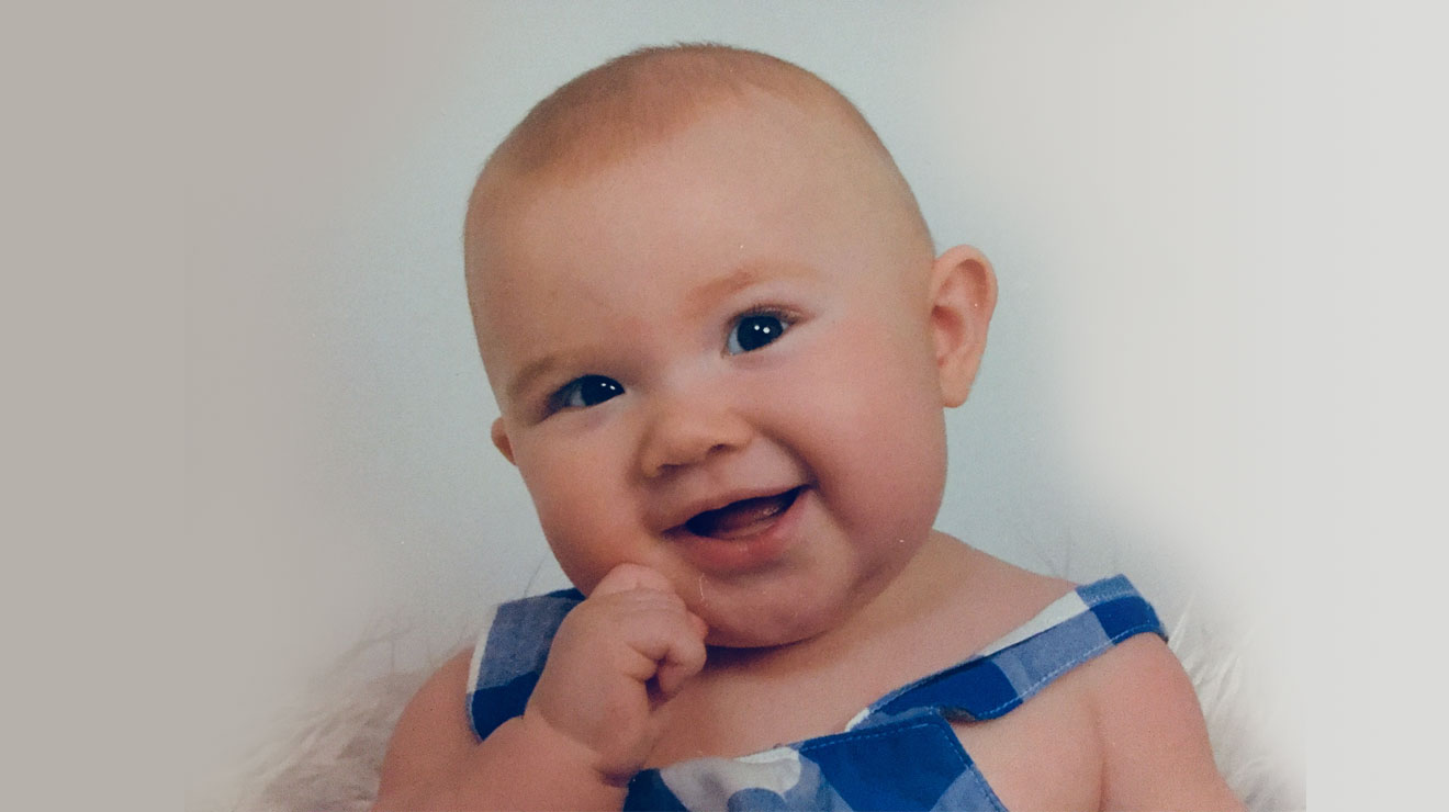 smiling baby wearing white and blue checkered top