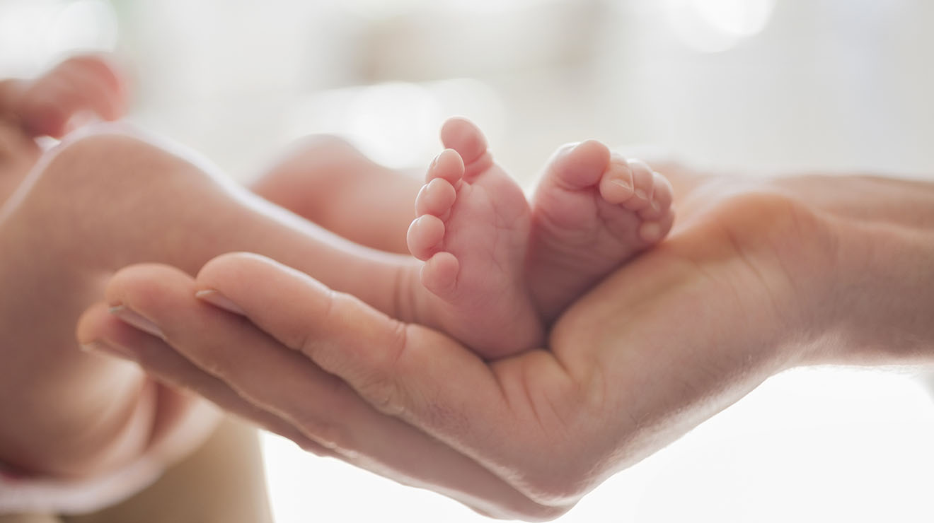 Mother's hand cradling baby's feet.