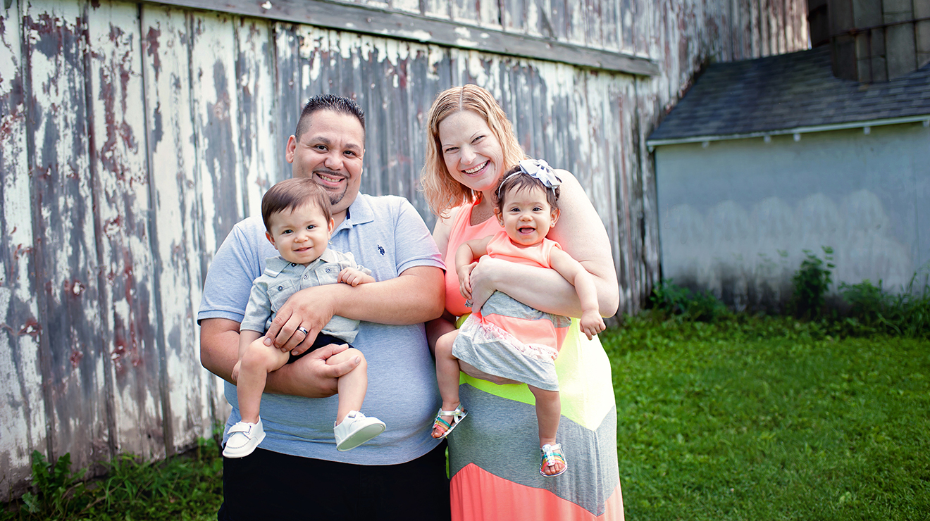 Smiling om and dad holding happy boy girl twins.