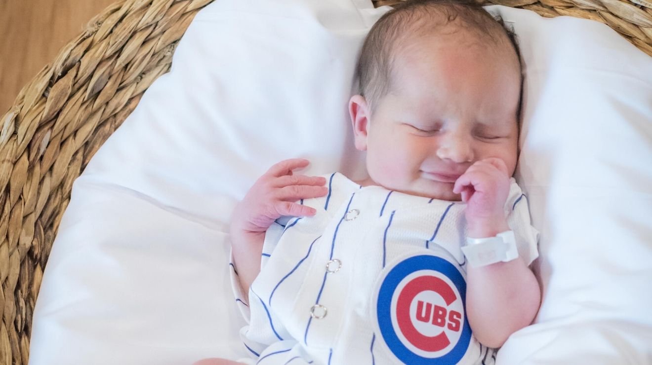 Newborn baby boy wearing a striped Chicago Cubs onesie